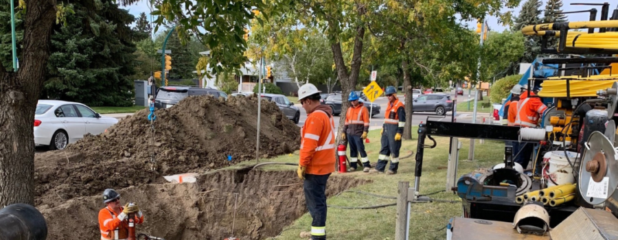Photo of a crew wearing MWG FR Clothing. Workers are wearing bright orange tops with silver segmented reflective tape on torso and sleeves to meet high-visibility standard CSA Z96-15. Workers are wearing FR Clothing because they are working in a hazardous environment.